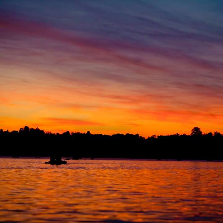 silhouette di 2 persone in sella a una barca sul mare durante il tramonto puzzle online