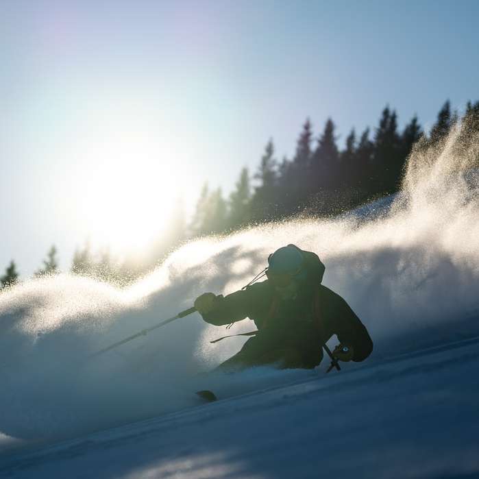 Persona con chaqueta negra y pantalones montando en snowboard puzzle deslizante online