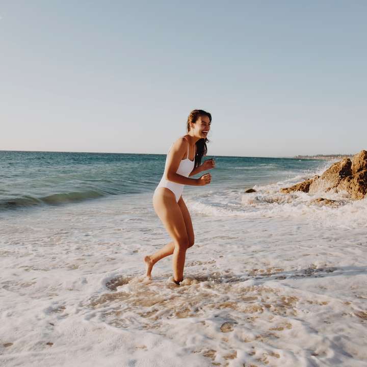 γυναίκα με λευκό μπικίνι που στέκεται στην παραλία κατά τη διάρκεια της ημέρας online παζλ
