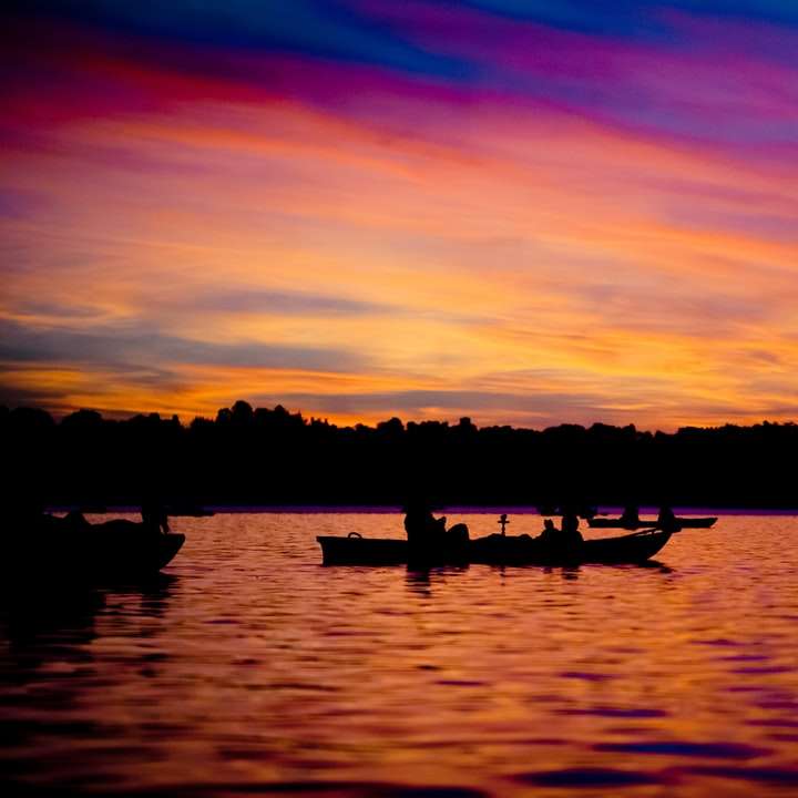 sylwetka ludzi płynących łodzią po jeziorze podczas zachodu słońca puzzle przesuwne online