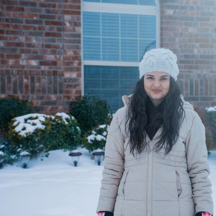 Frau im weißen Wintermantel, die auf schneebedecktem Boden steht Online-Puzzle