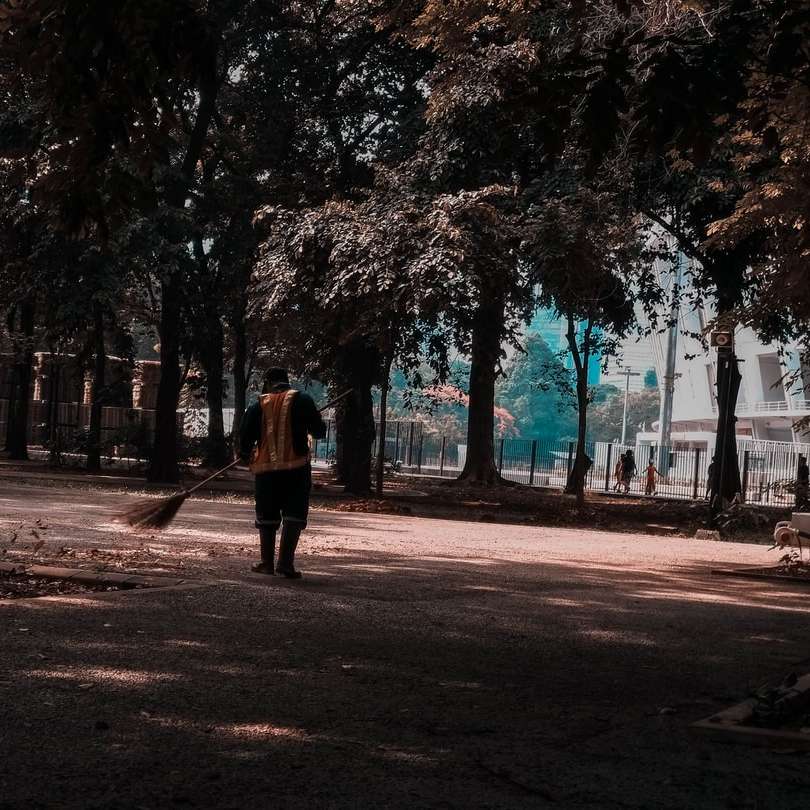 Mujer de abrigo marrón caminando por el sendero rodeado de árboles puzzle deslizante online