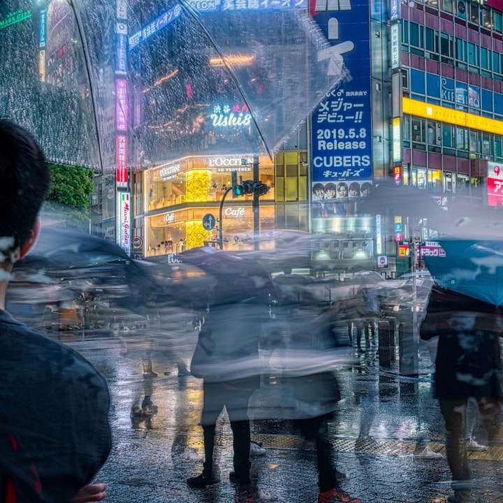 людина в чорній куртці тримає парасольку, що йде по тротуару онлайн пазл