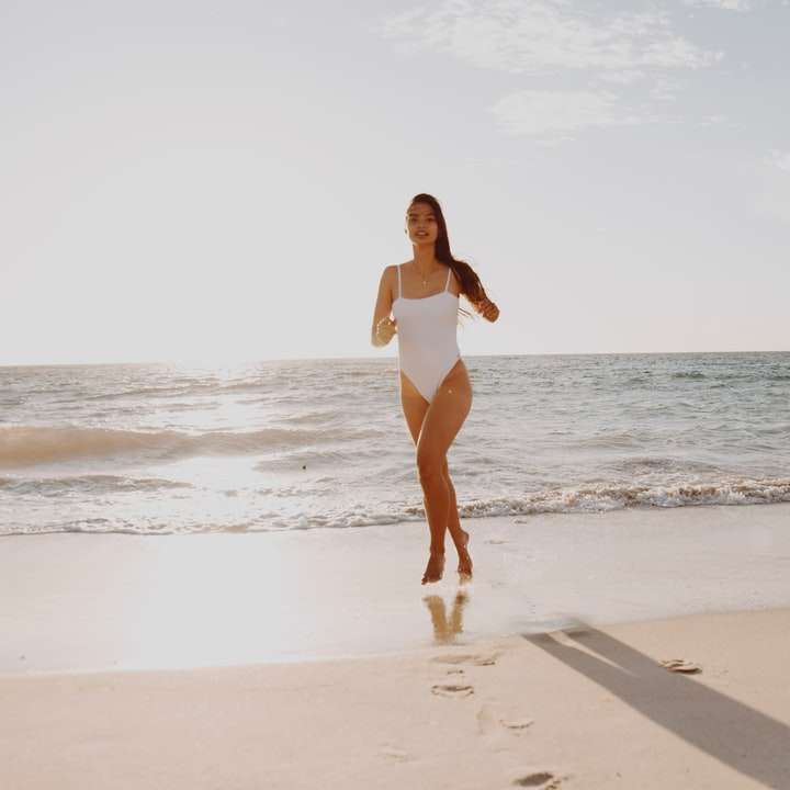 昼間にビーチに立っている白いビキニの女性 オンラインパズル