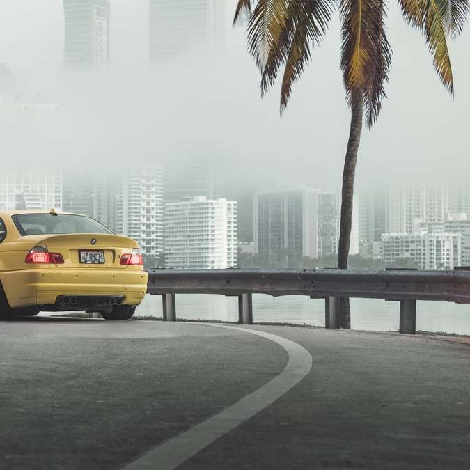 желтый седан на дороге возле городских зданий в дневное время раздвижная головоломка онлайн