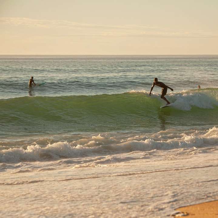 uomo surf sulle onde del mare durante il giorno puzzle scorrevole online