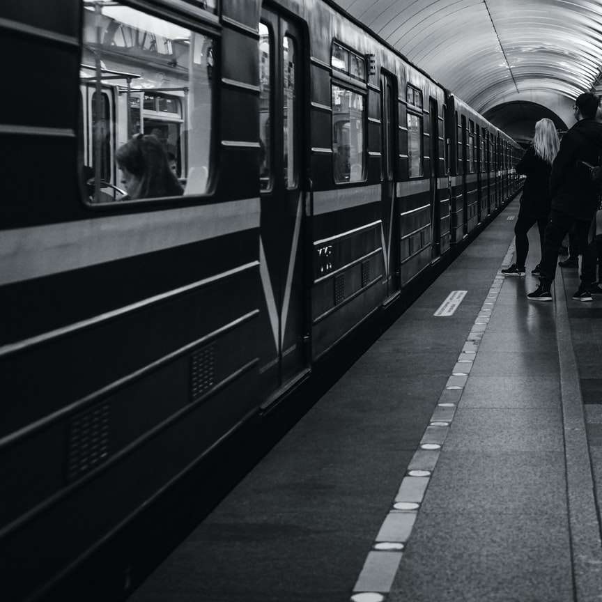 grayscale photo of people walking on train station sliding puzzle online