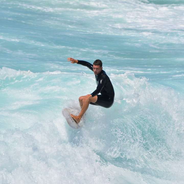 kvinna i svart våtdräkt som surfar på havsvågor under dagtid Pussel online