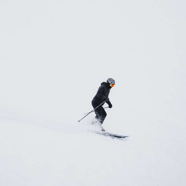 homem de jaqueta preta e calça preta andando de lâminas de esqui puzzle online