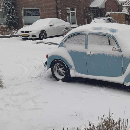 Volkswagen Beetle bleu garé sur un sol couvert de neige puzzle en ligne