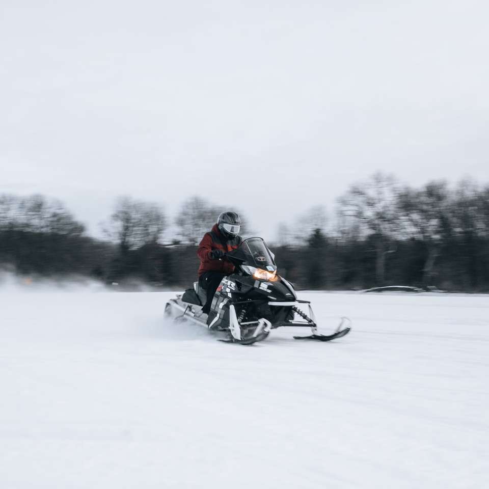 Homme à cheval sur une moto noire sur un champ couvert de neige puzzle coulissant en ligne