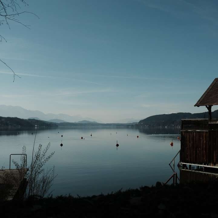 hnědý dřevěný dům na jezeře během dne posuvné puzzle online