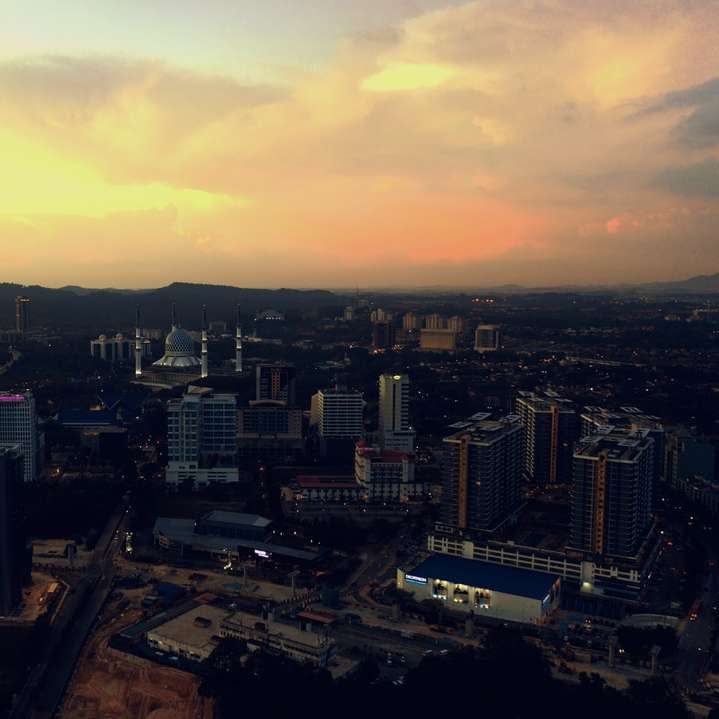 orizontul orașului în timpul apusului soarelui cu cer înnorat puzzle online