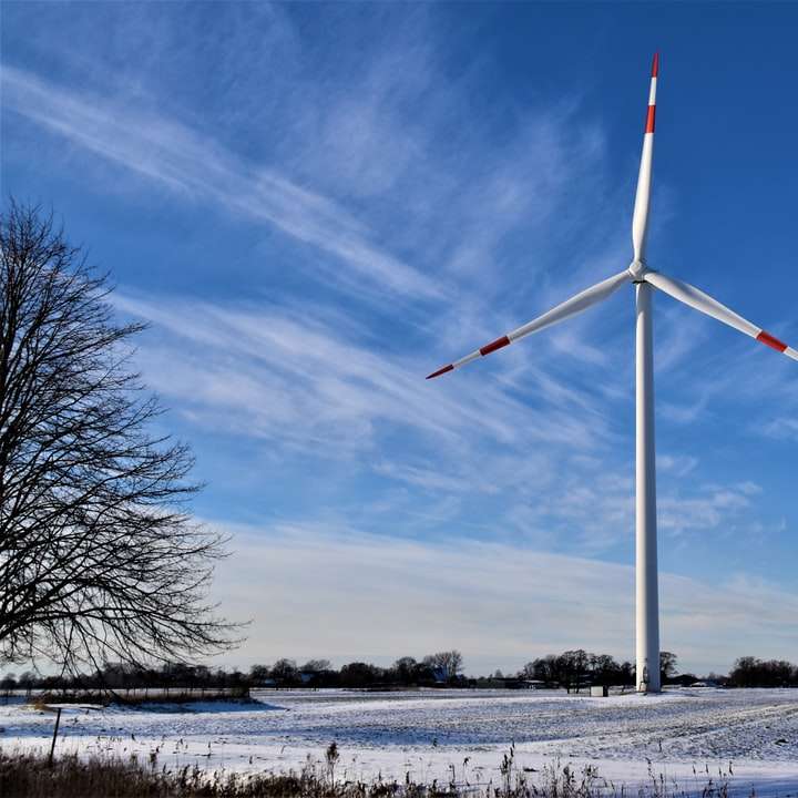 bílá větrná turbína na sněhem pokryté zemi pod modrou oblohou posuvné puzzle online