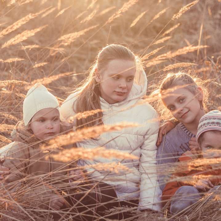 3 dziewczynki leżące w ciągu dnia na wyschniętej brązowej trawie puzzle przesuwne online