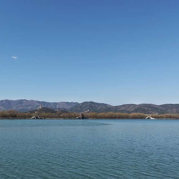 водоем близо до планина под синьо небе през деня плъзгащ се пъзел онлайн