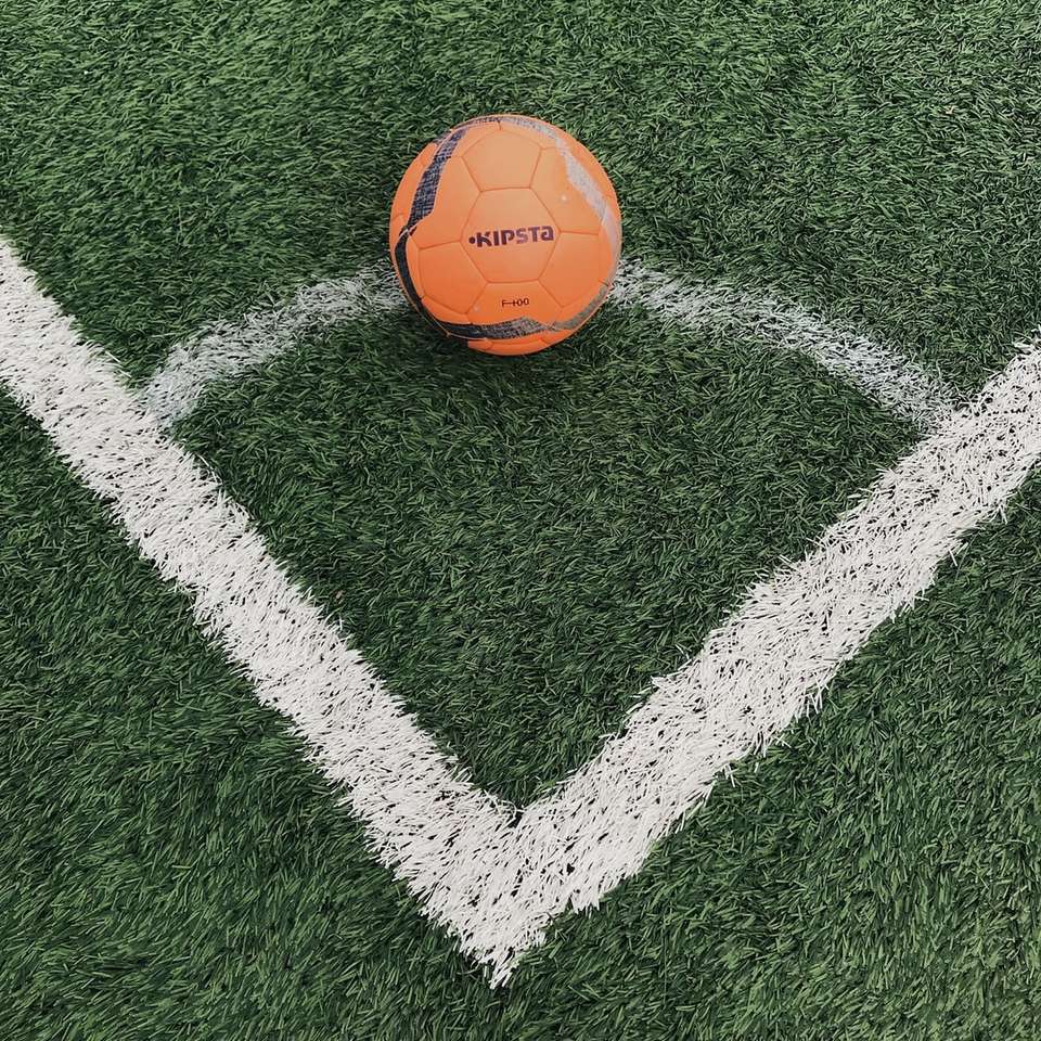 πορτοκαλί μπάλα ποδοσφαίρου στο πεδίο πράσινο γρασίδι συρόμενο παζλ online