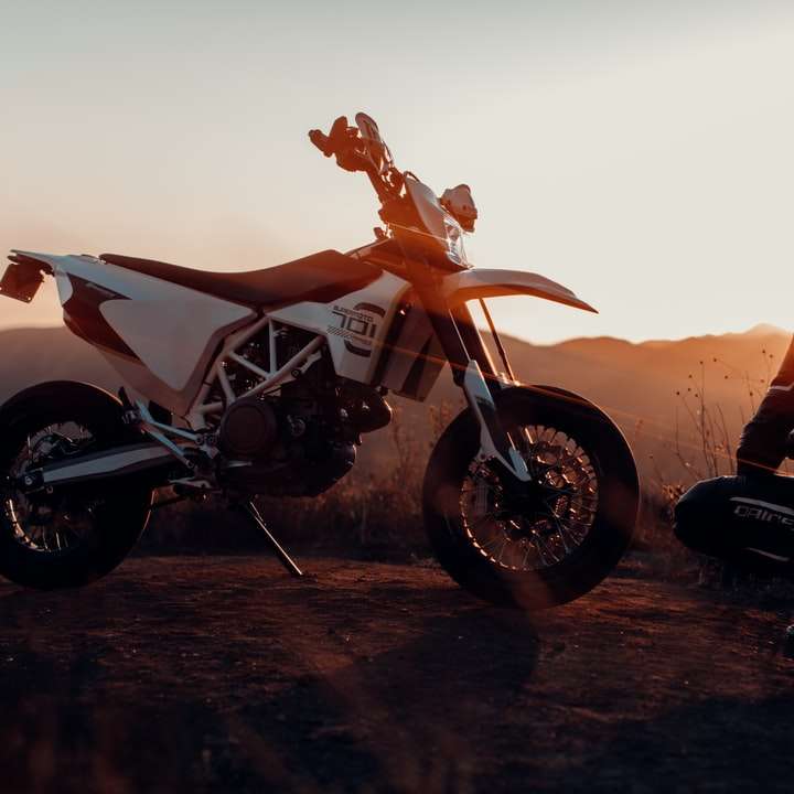 man i svart jacka sitter på motorcykel under solnedgången glidande pussel online