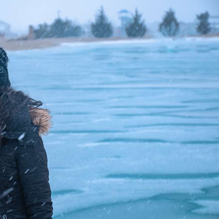 Frau in der schwarzen Jacke, die auf schneebedecktem Boden steht Schiebepuzzle online