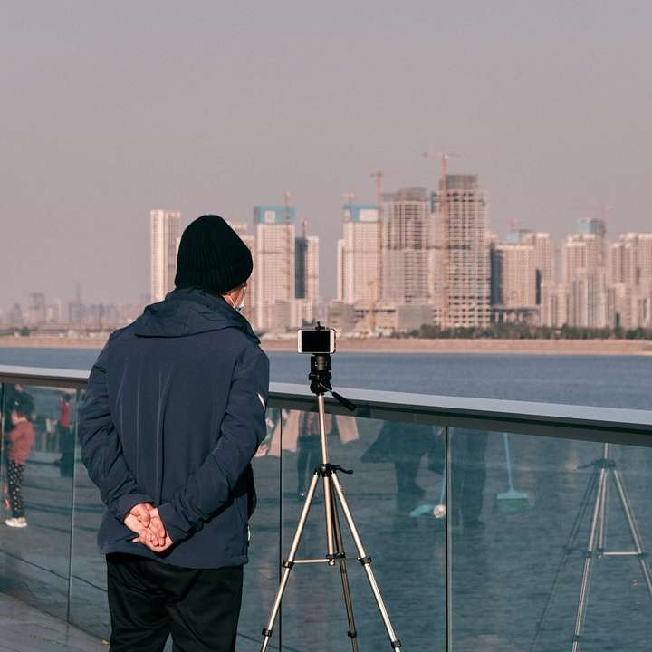 мъж в черно яке, стоящ на върха на сградата и гледащ онлайн пъзел