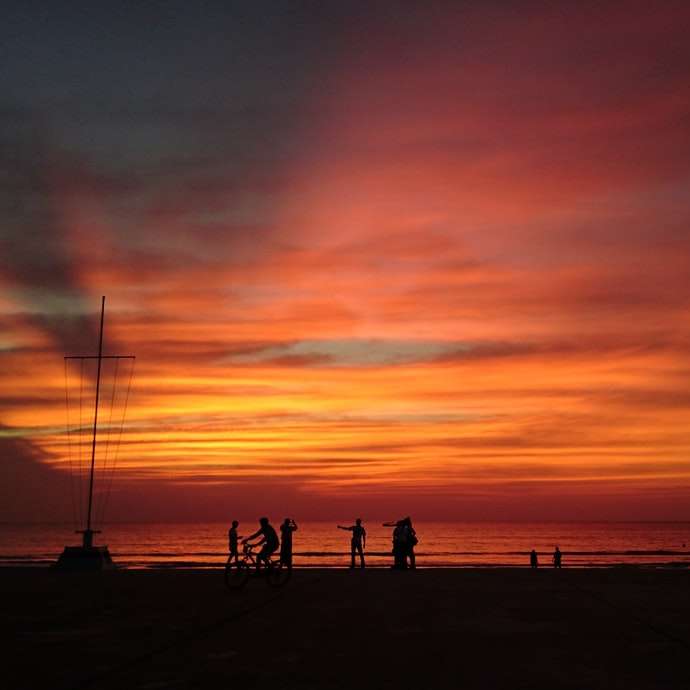 日没時にビーチに立っている人々のシルエット スライディングパズル・オンライン