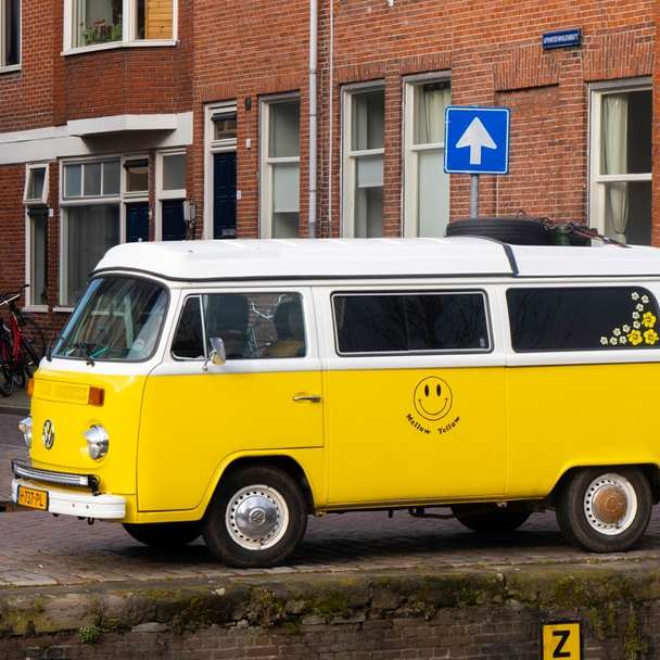 żółto-biały volkswagen t-2 van zaparkowany obok białego betonowego budynku puzzle online
