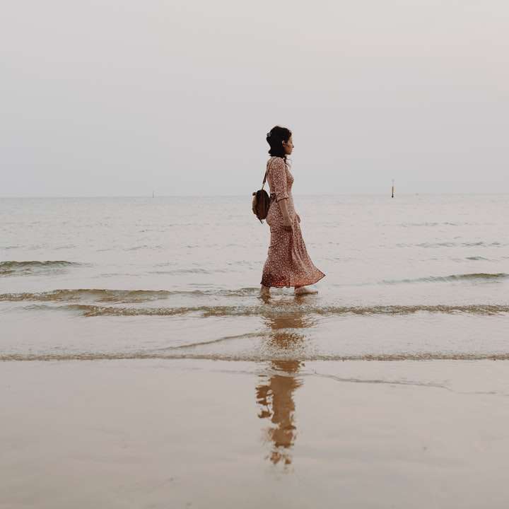 nő rózsaszín ruhában, séta a tengerparton napközben csúszó puzzle online