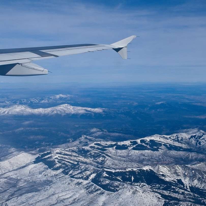 Ala de avión blanco sobre montañas cubiertas de nieve puzzle deslizante online