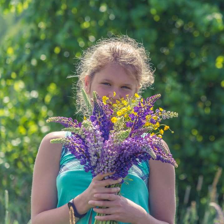 dívka v modrých šatech bez rukávů drží fialový květ online puzzle
