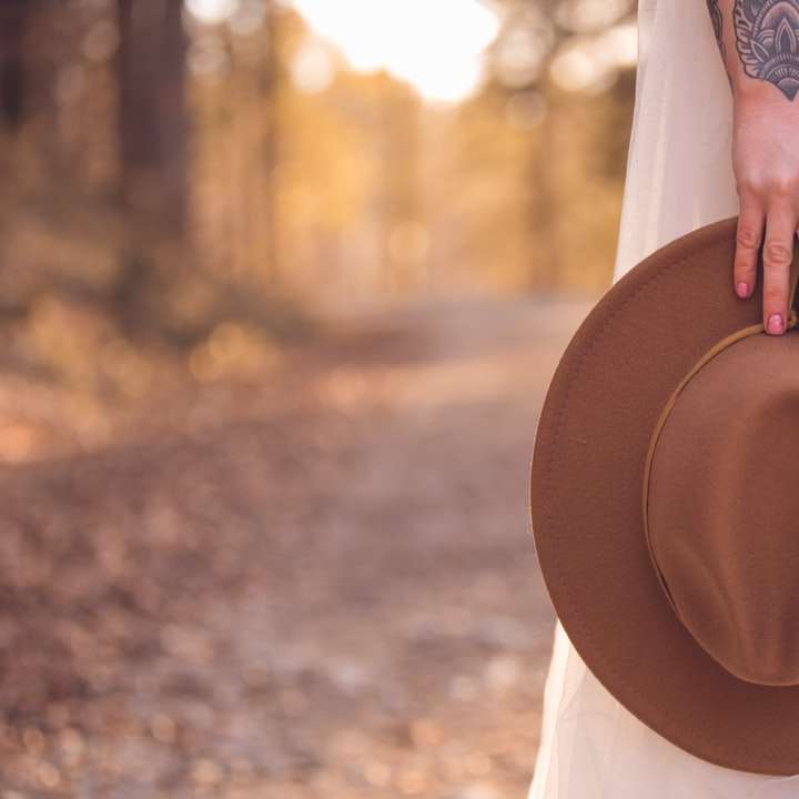 femme en chemise à manches longues blanche tenant un chapeau marron puzzle coulissant en ligne