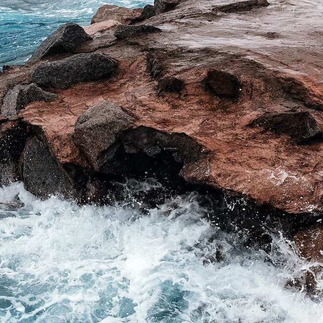 formação de rocha marrom ao lado do corpo d'água durante o dia puzzle deslizante online