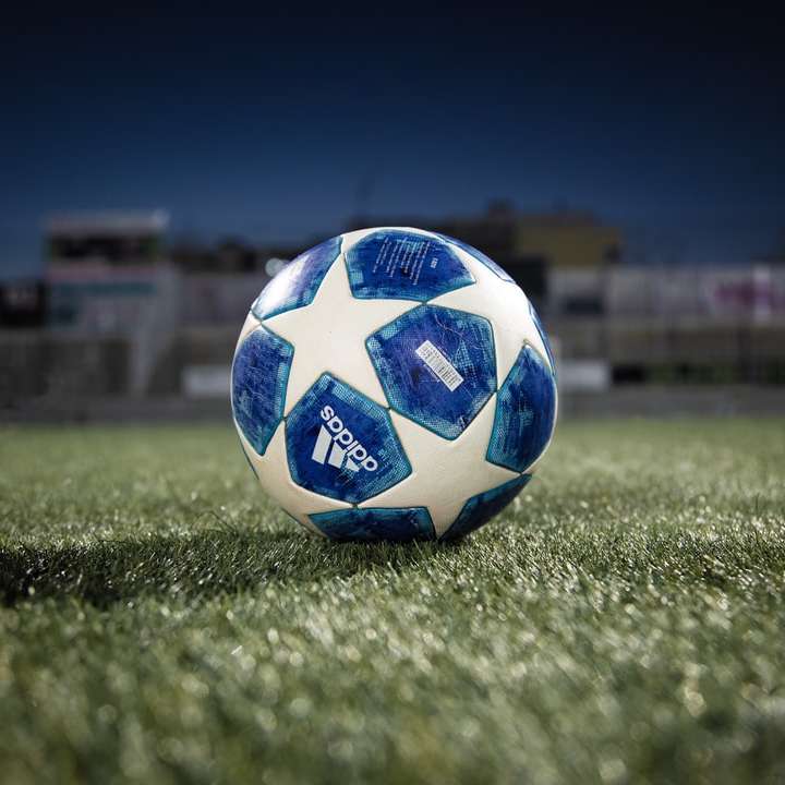 Ballon de football bleu blanc sur terrain d'herbe verte pendant la journée puzzle coulissant en ligne