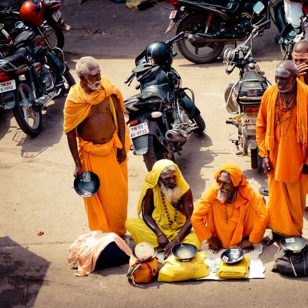 ludzie w pomarańczowych szatach stojących na motocyklu w ciągu dnia puzzle online