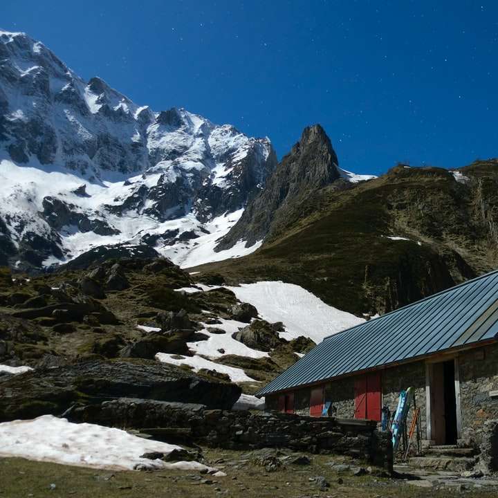 brązowy drewniany dom w pobliżu zaśnieżonej góry w ciągu dnia puzzle online