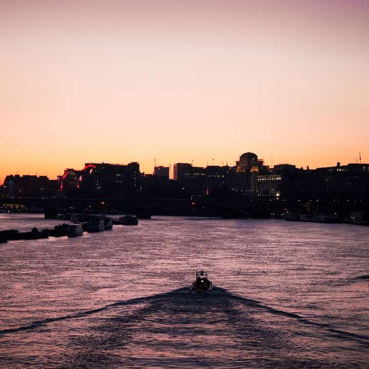 човек, който се вози на лодка по вода близо до градските сгради онлайн пъзел