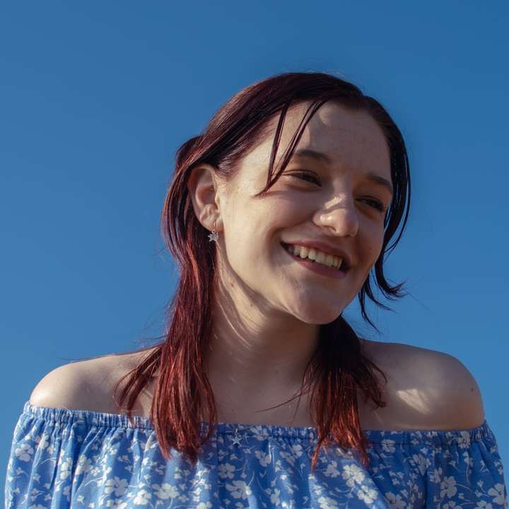 glimlachende vrouw in blauwe en witte bloemenbuisjurk schuifpuzzel online