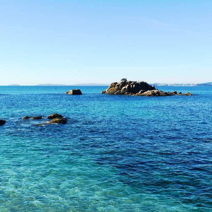 skalnaté pobřeží pod modrou oblohou během dne posuvné puzzle online