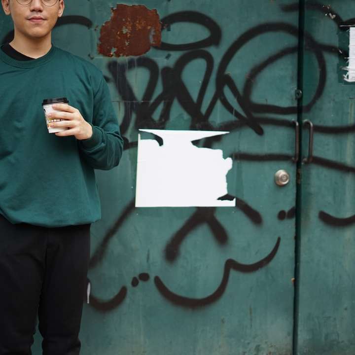 Homme en pull vert tenant du papier d'imprimante blanc puzzle en ligne