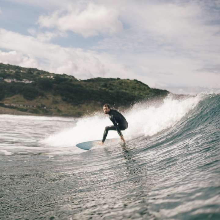 muž surfování na moři během dne online puzzle
