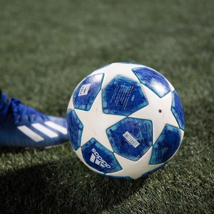 Balón de fútbol azul y blanco en el campo de hierba verde puzzle deslizante online