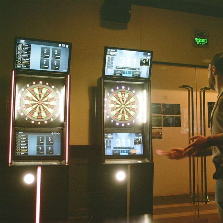 mężczyzna w brązowej kurtce stojący w pobliżu czarnego telewizora z płaskim ekranem puzzle online