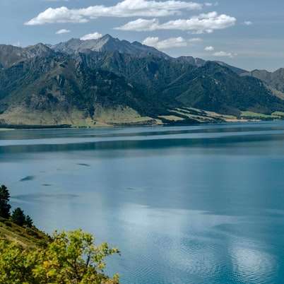 синьо езеро близо до заснежена планина през деня плъзгащ се пъзел онлайн