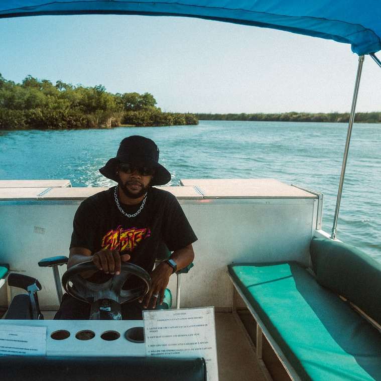 mężczyzna w czarno-żółtej koszulce z okrągłym dekoltem siedzi na łodzi puzzle przesuwne online