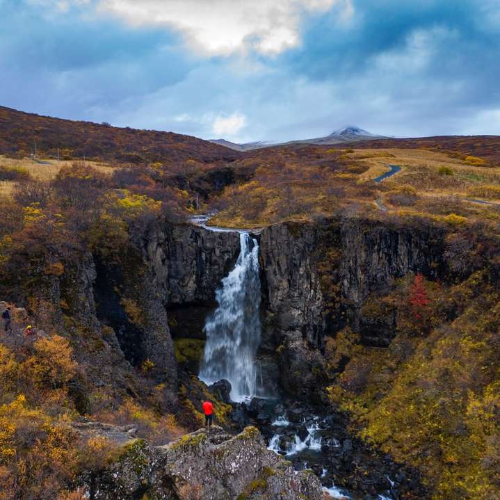 cachoeiras na montanha rochosa marrom sob céu branco nublado puzzle deslizante online