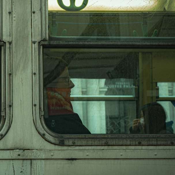電車の窓の前に立っている赤いジャケットの男 スライディングパズル・オンライン