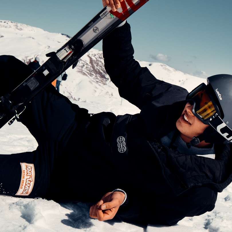 homem de jaqueta preta segurando uma prancha de esqui de neve vermelha e preta puzzle deslizante online