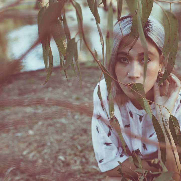 κορίτσι με λευκό μακρυμάνικο πουκάμισο στέκεται κοντά σε πράσινο φυτό online παζλ