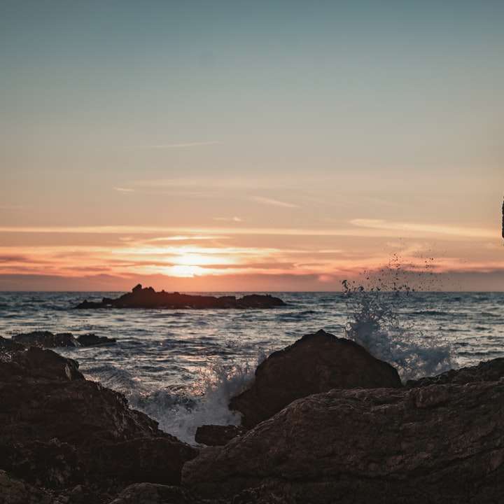 silueta muže stojícího na skalním útvaru poblíž těla posuvné puzzle online