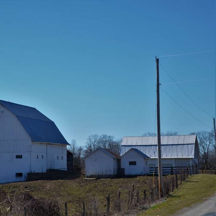 maison blanche et grise près de champ d'herbe verte sous le ciel bleu puzzle coulissant en ligne