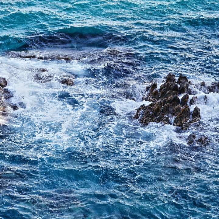 havsvågor som kraschar på stenar under dagtid glidande pussel online